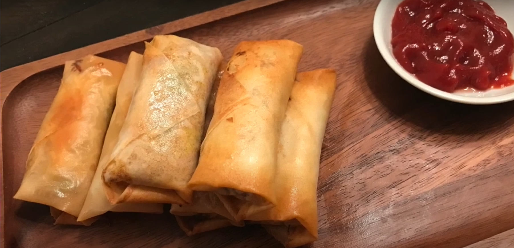 spring rolls in a serving dish with ketchup