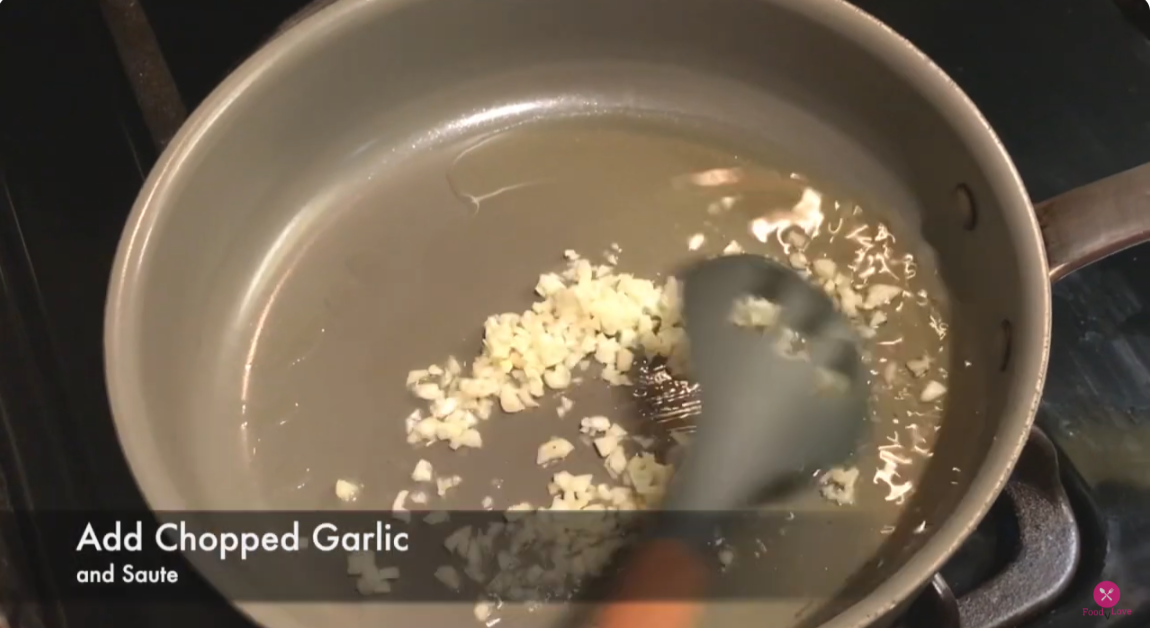 a pan on the stove with oil and chopped garlic 