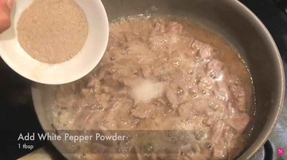 adding white pepper to the cooking beef