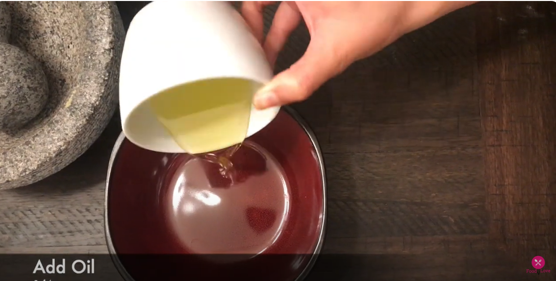 a hand pouring oil from one bowl to another