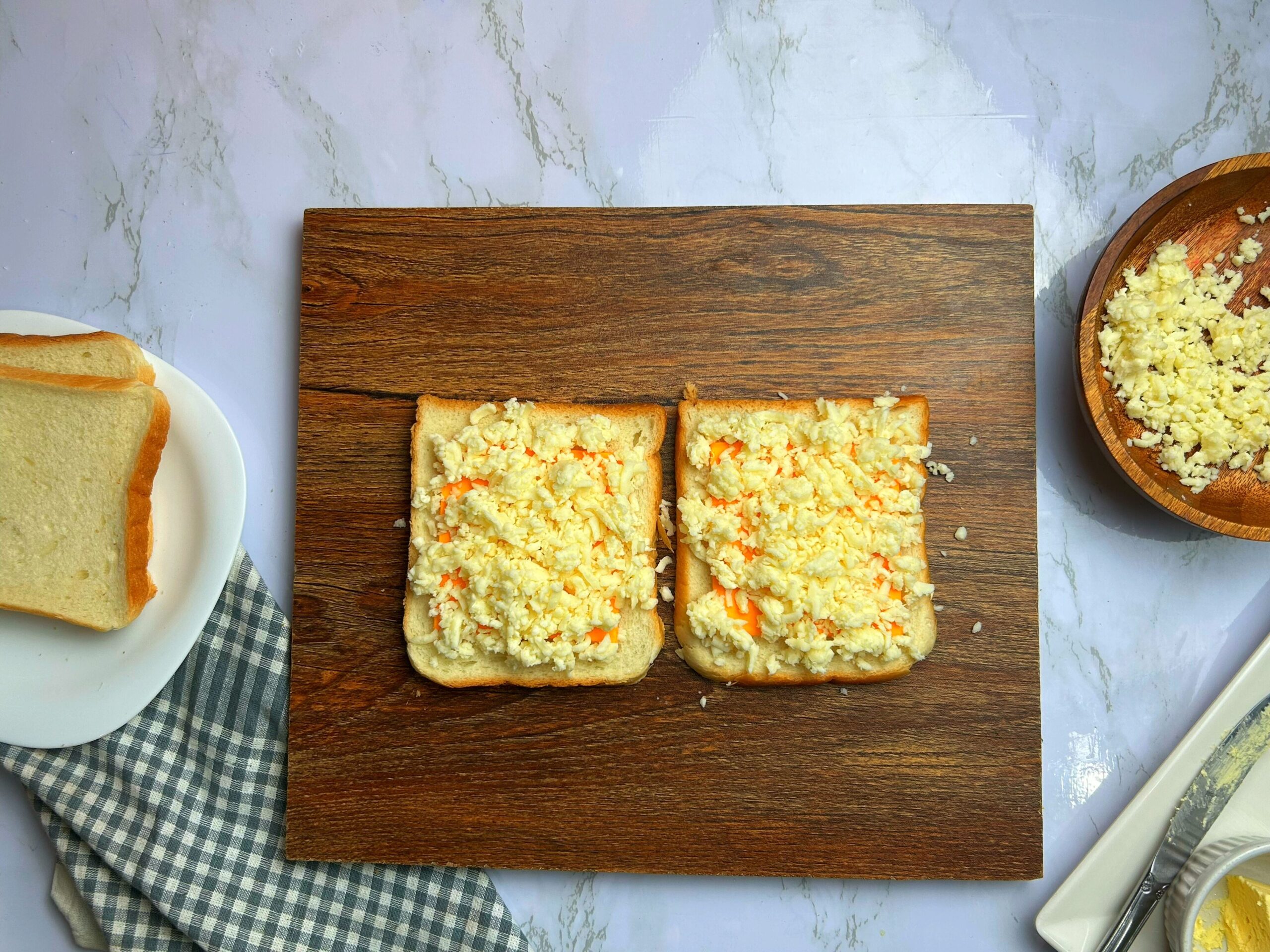 spreading shredded and sliced cheese on the bread