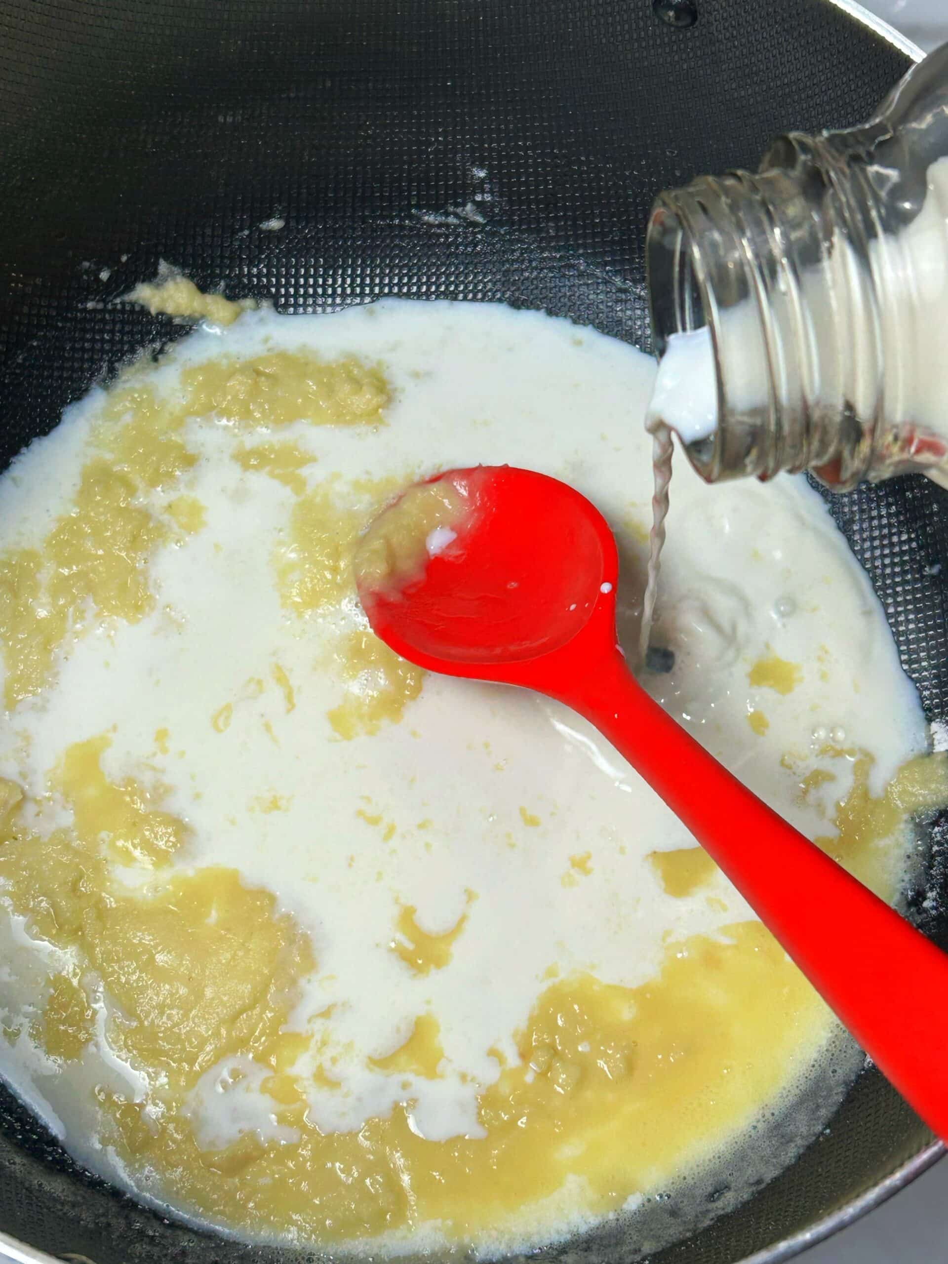 adding milk in frying pan for white sauce