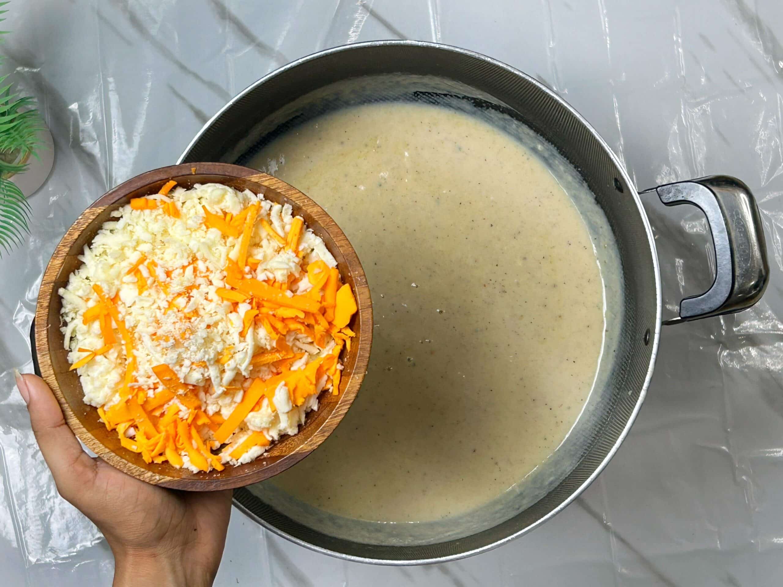 adding shredded cheese to the white sauce